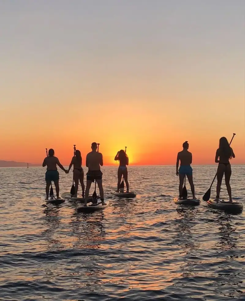 Grupo de paddle surf al atardecer